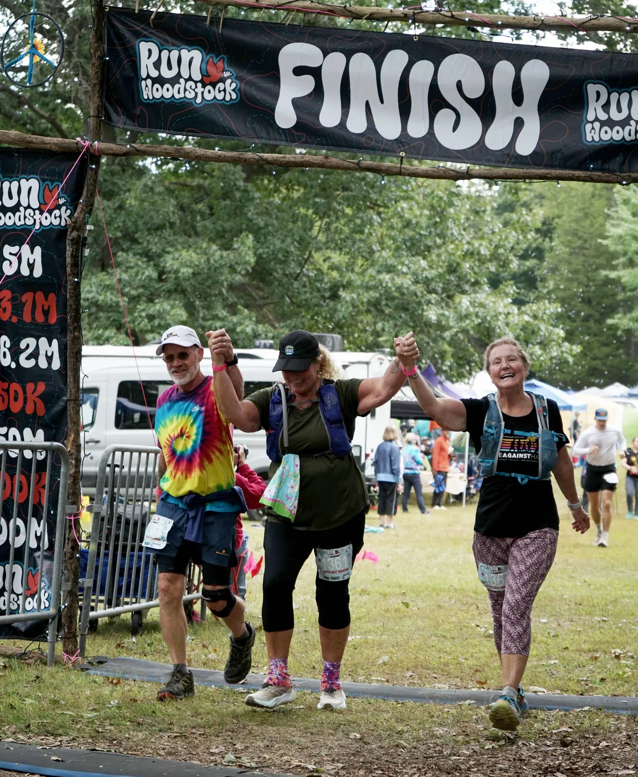 Three runners crossing the finish line, holding hands and celebrating.