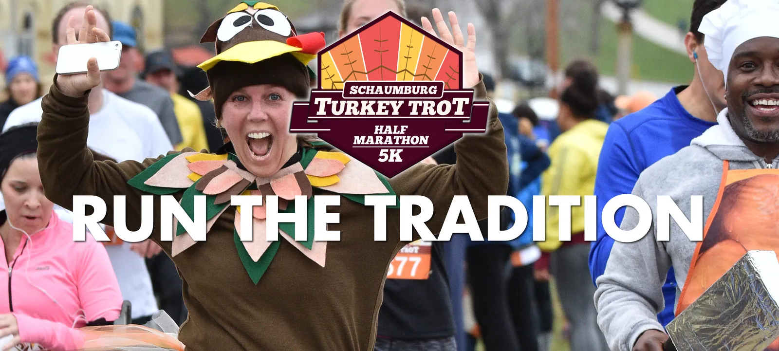 A runner in a turkey costume with arms raised in excitement, with the text 'RUN THE TRADITION' overlaid on the image, during the Schaumburg Turkey Trot Half Marathon & 5K.