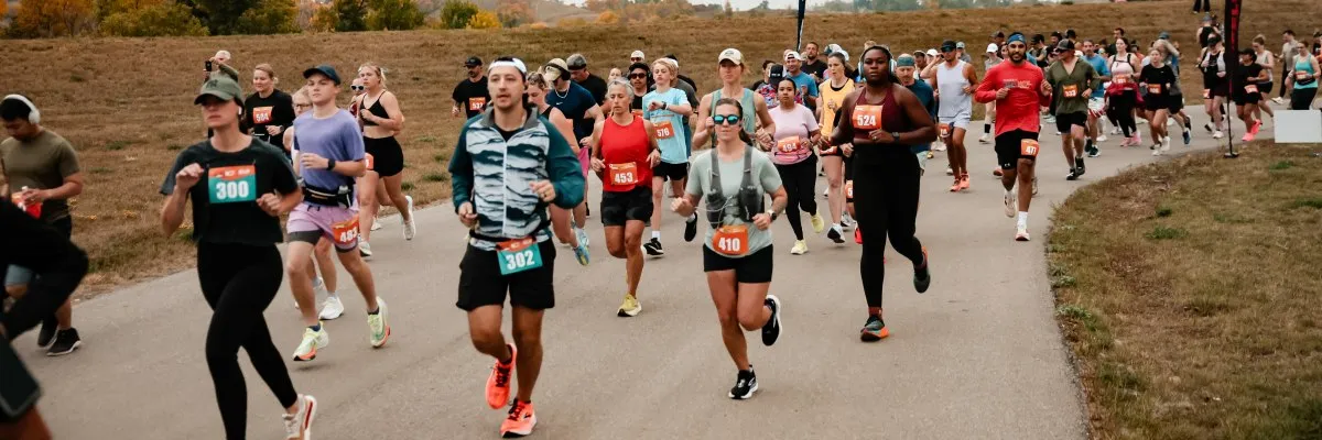 A group of runners are starting a race on a paved path with grassy areas on either side.