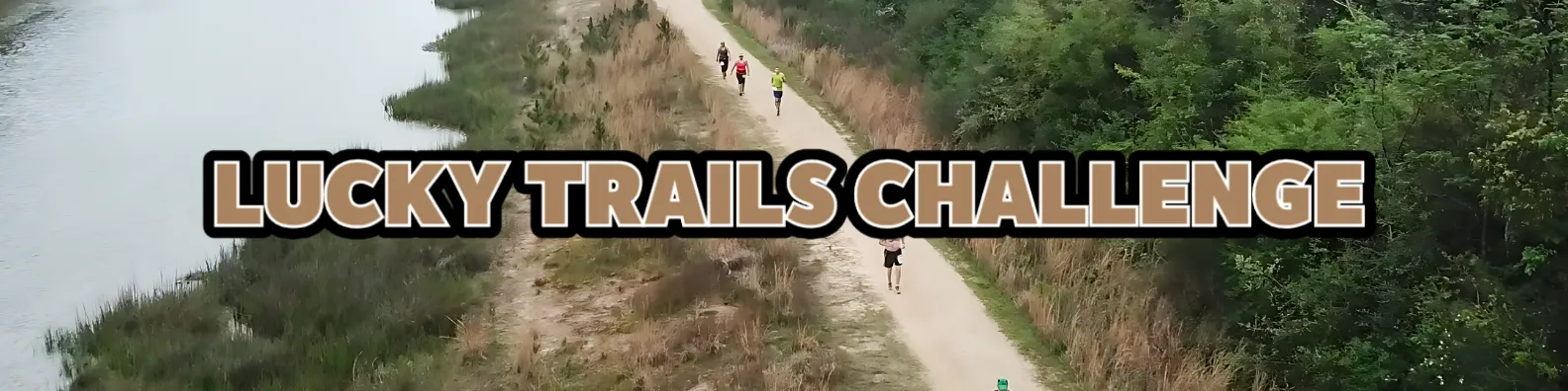 Runners on a trail next to a body of water with the text "LUCKY TRAILS CHALLENGE" overlaid.