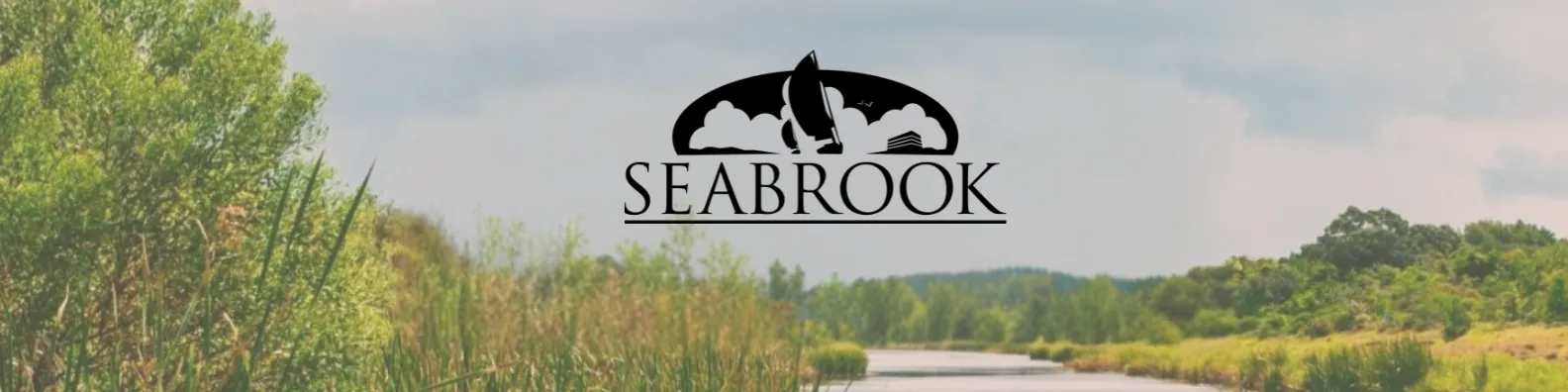 Scenic waterfront view with trees and hills, featuring the Seabrook logo.