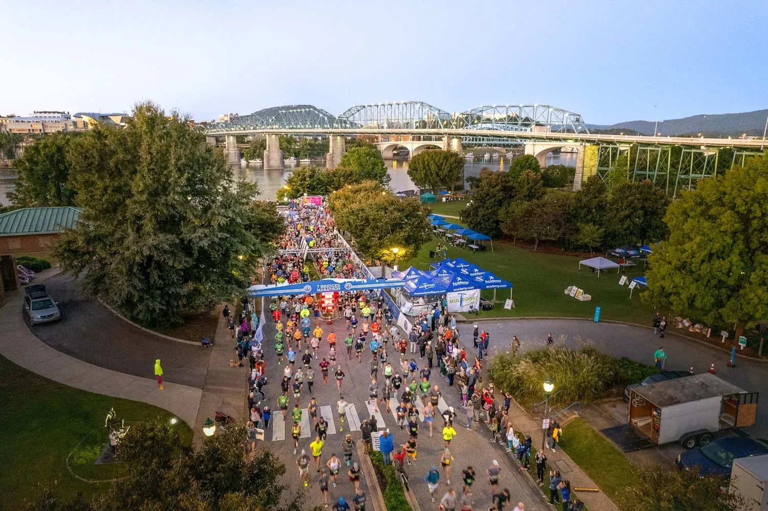 A large group of runners starting the Seven Bridges Marathon with iconic bridges in the background.
