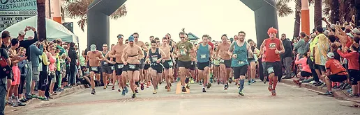 Runners starting a race under an archway, with spectators cheering on the sides.