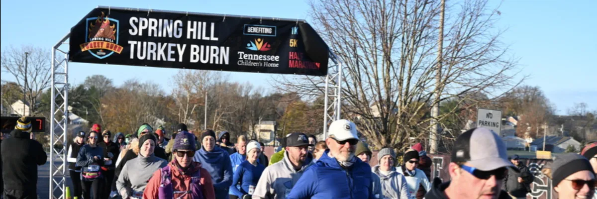 Runners gather at the start line under the Spring Hill Turkey Burn banner.