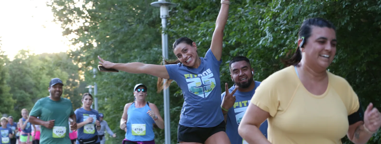 Runners celebrating during a race, with one runner in the foreground raising her arms in excitement.
