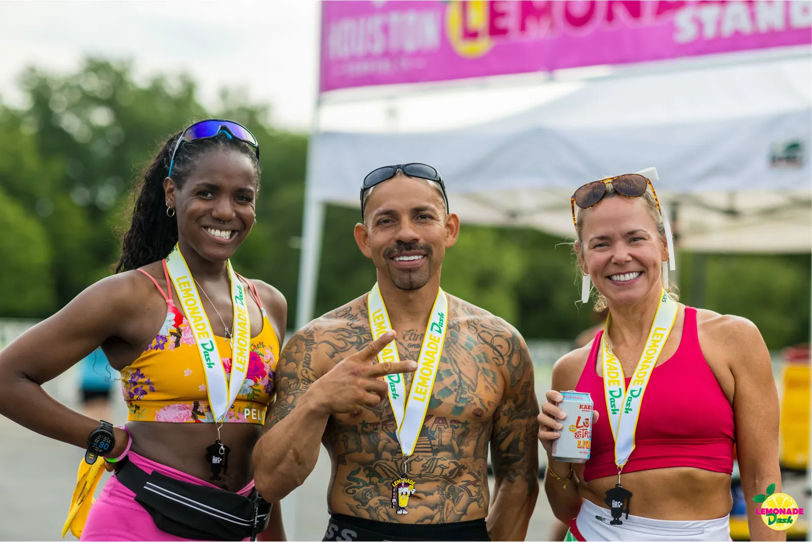 Three smiling runners, two women and one man, wearing race medals and athletic wear, posing for a photo after a race.