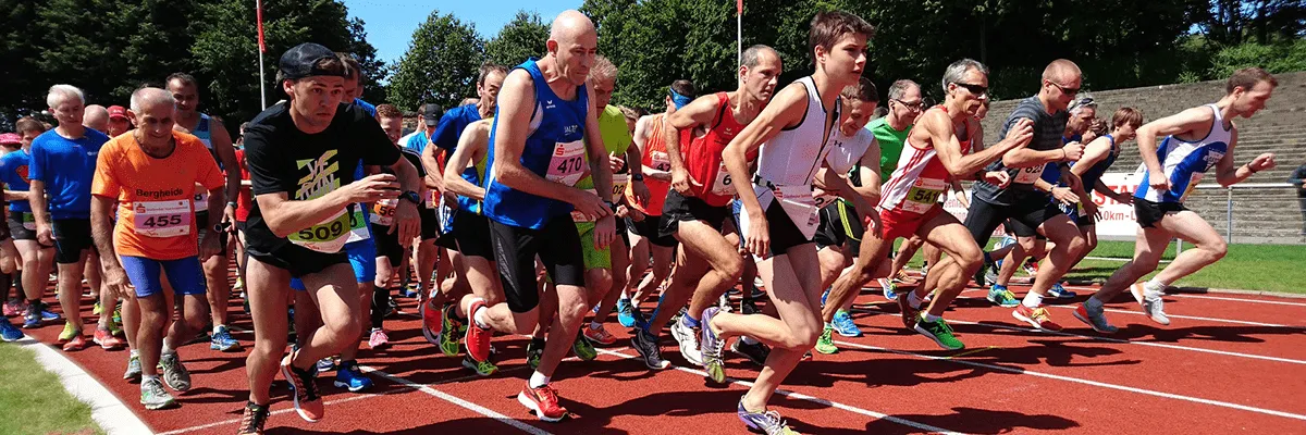 Runners in a race starting on a track, with bib numbers visible.