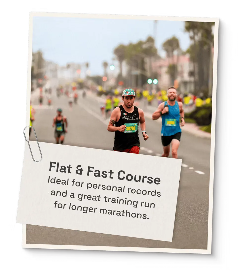 Two runners on a road course, with a sign that says "Flat & Fast Course".