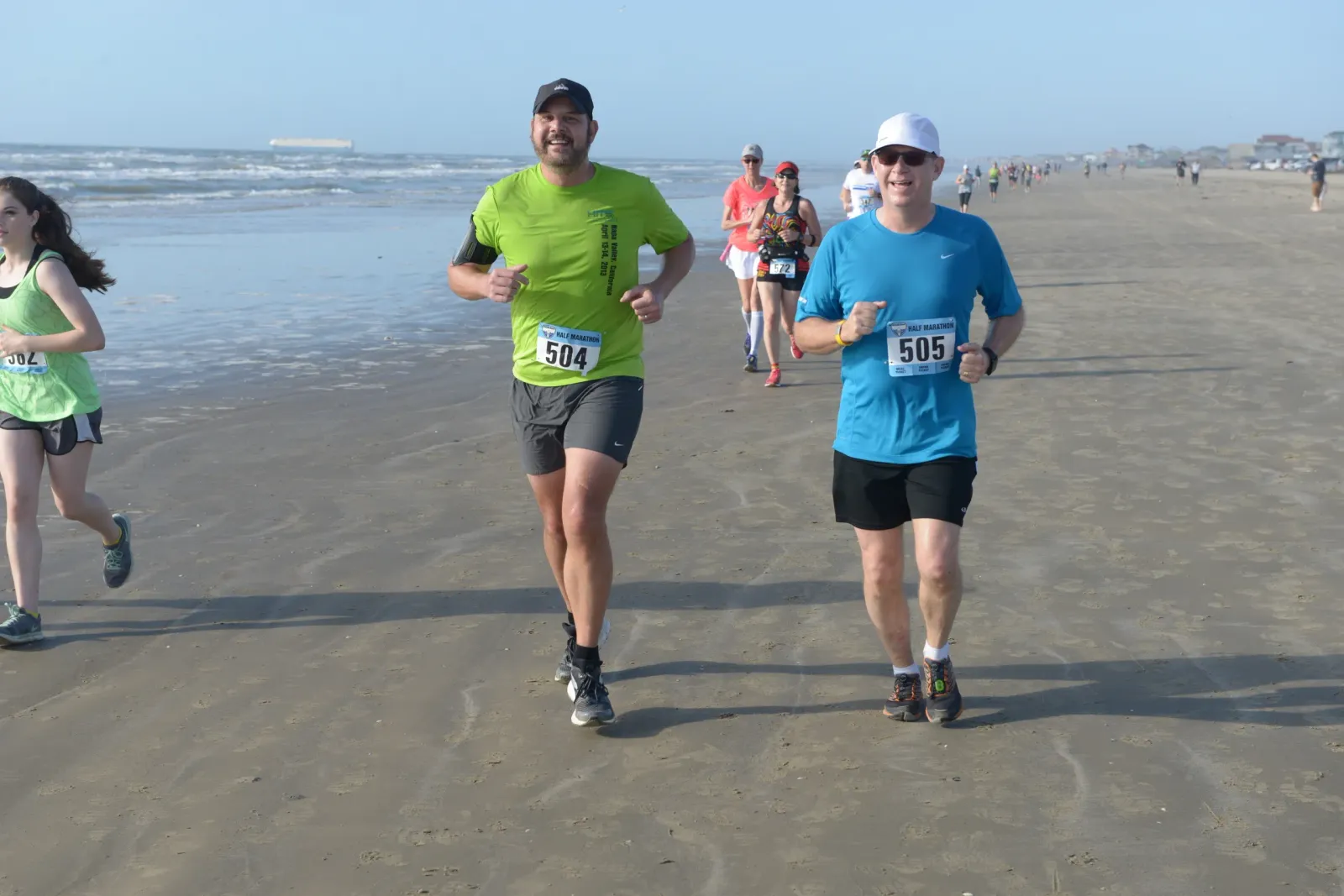 Runners on a beach during a half marathon, with the ocean in the background.