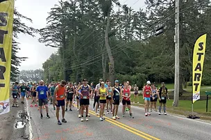 Runners gathered at the start line of a road race, with start banners visible.