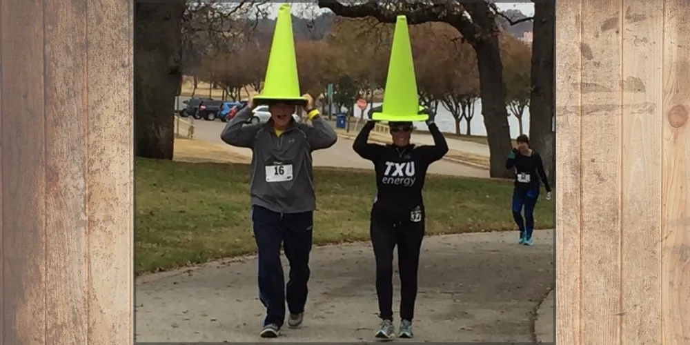 Two runners wearing bright yellow traffic cones on their heads during a race.