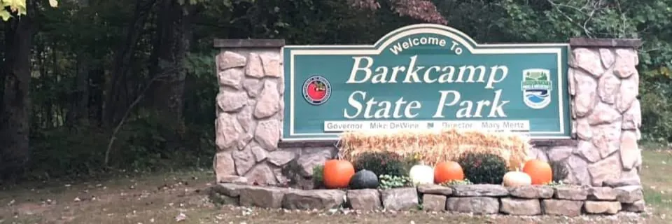 Welcome to Barkcamp State Park sign with pumpkins and hay bales in front.