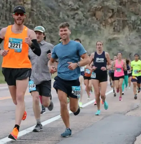 Runners participating in a race, with several individuals in the foreground and more in the background on a road course.