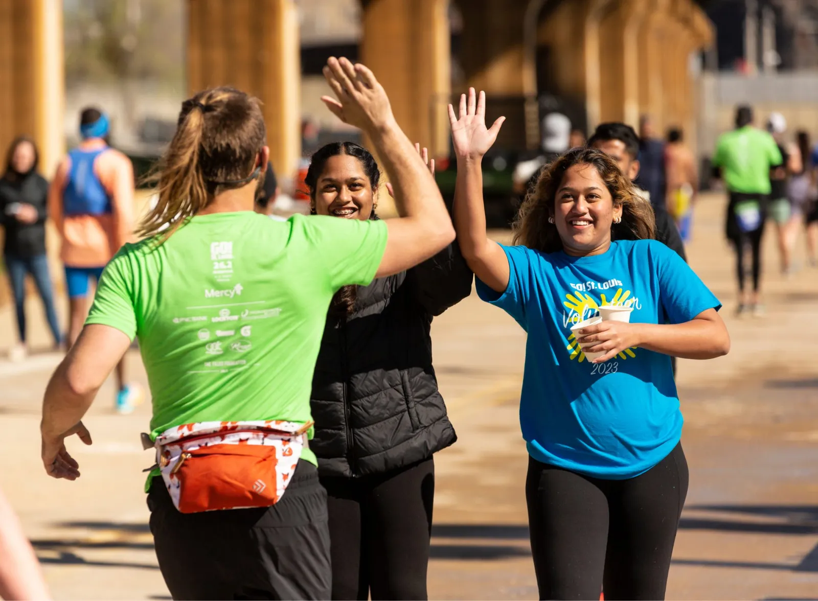 Three runners high-fiving each other during a race, with smiles and a sense of accomplishment.