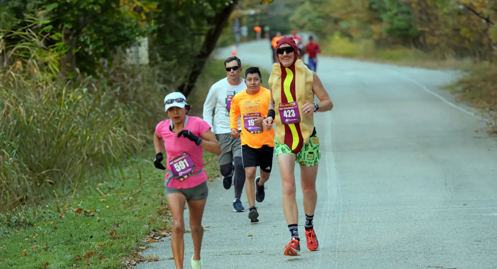 Runners participating in the Great Go St. Louis Halloween Race, with one runner in a hot dog costume.