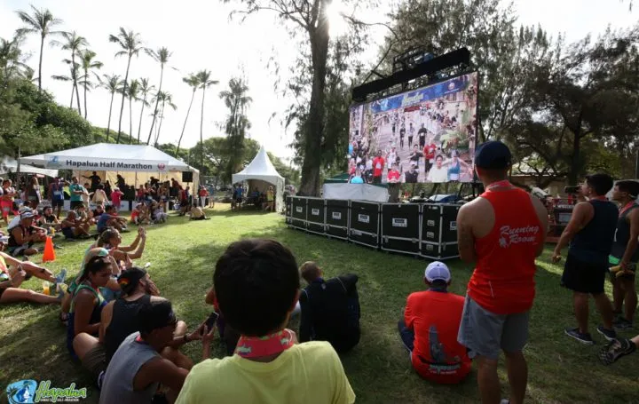 Spectators watch a large screen displaying runners at the Hapalua Half Marathon.