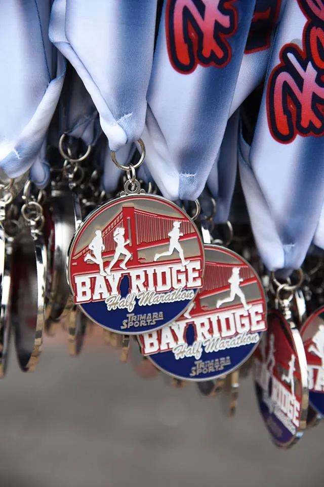 Close-up of Bay Ridge Half Marathon medals, showing runners silhouetted against a bridge.