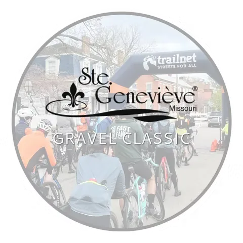 Cyclists gathered at the start line of the Ste. Genevieve Gravel Classic, with a race arch overhead.