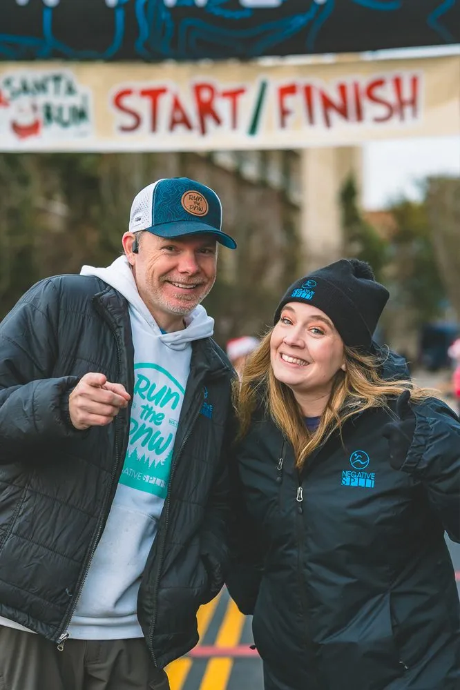 A man and a woman smiling at the start/finish line of a race.