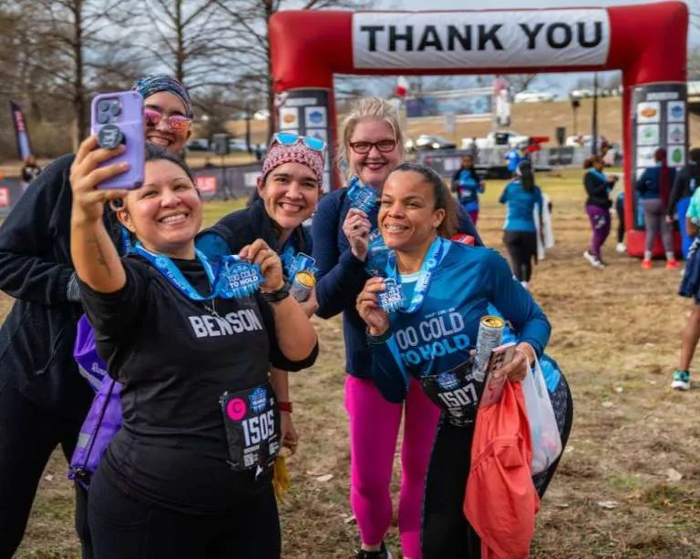 A group of women smiling and taking a selfie with their race medals after finishing the Too Cold To Hold 5k/10k/Half Marathon.