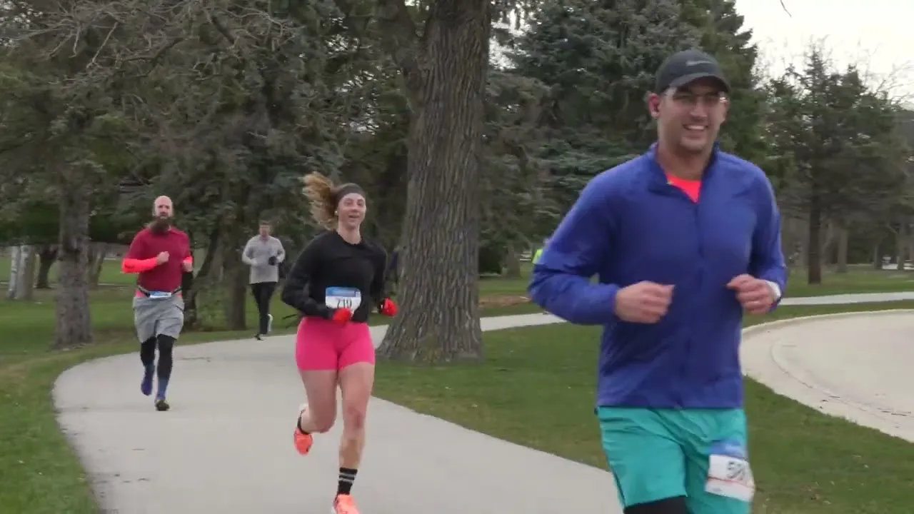 Three runners on a paved path in a park, with trees and grass in the background.