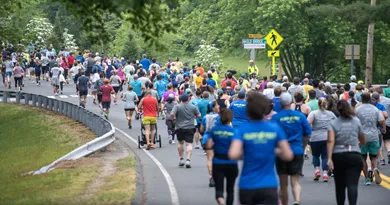A large group of runners participating in a road race, with many wearing blue shirts.