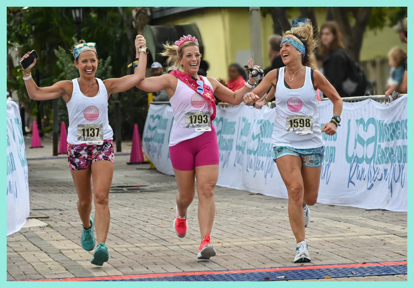 Three women celebrating as they cross the finish line of a half marathon.
