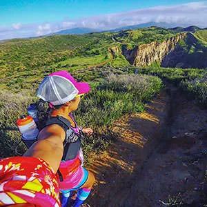 Runner on a trail with scenic hills in the background.
