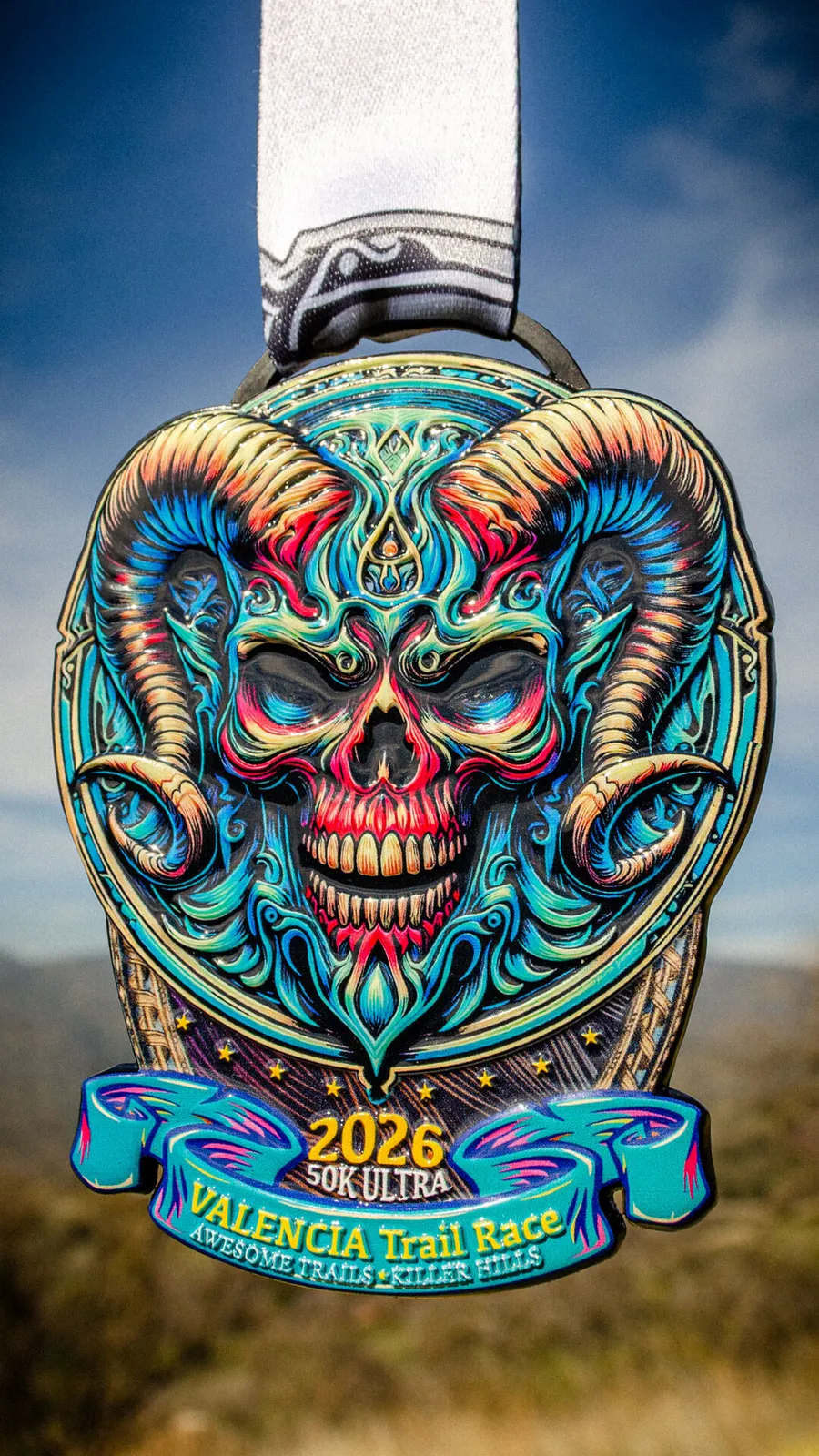 A colorful and intricately designed medal for the Valencia Trail Race 50K Ultra, featuring a skull with ram horns.