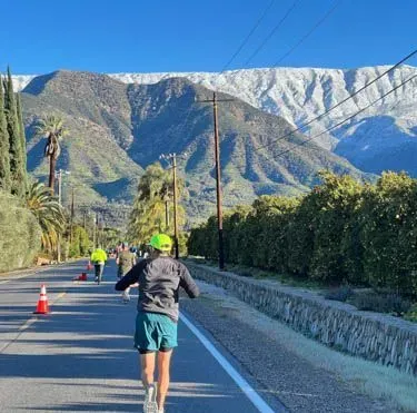 A runner runs on a road with mountains in the background during the Ventura Marathon.