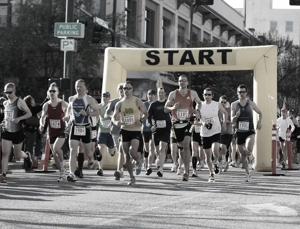 Runners starting a race under a yellow archway with 'START' written on it.