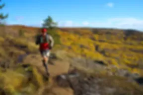 Runner on a trail with autumn foliage in the background.