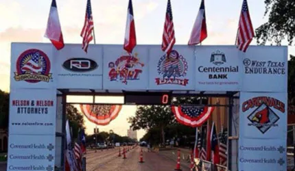 Decorated start/finish line archway with flags and sponsor logos for the Willie McCool Memorial Half Marathon.