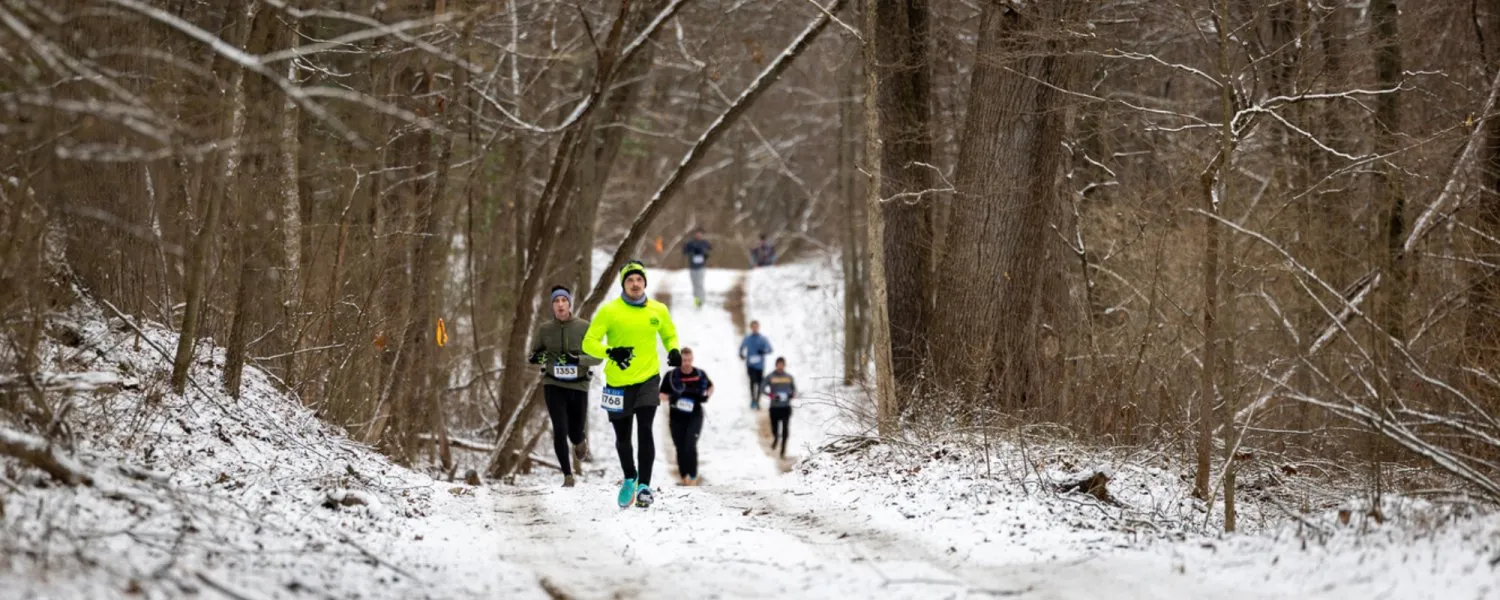 Runners on a snowy trail during a winter race.