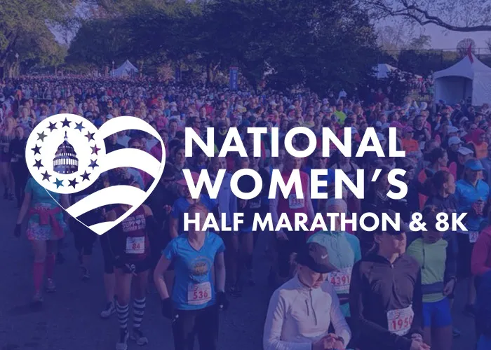 A large crowd of women runners at the start line of the National Women's Half Marathon & 8K, with the race logo and name overlaid.