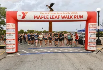 Runners gathered at the start line under a red inflatable arch for the YMCA Maple Leaf Walk Run.