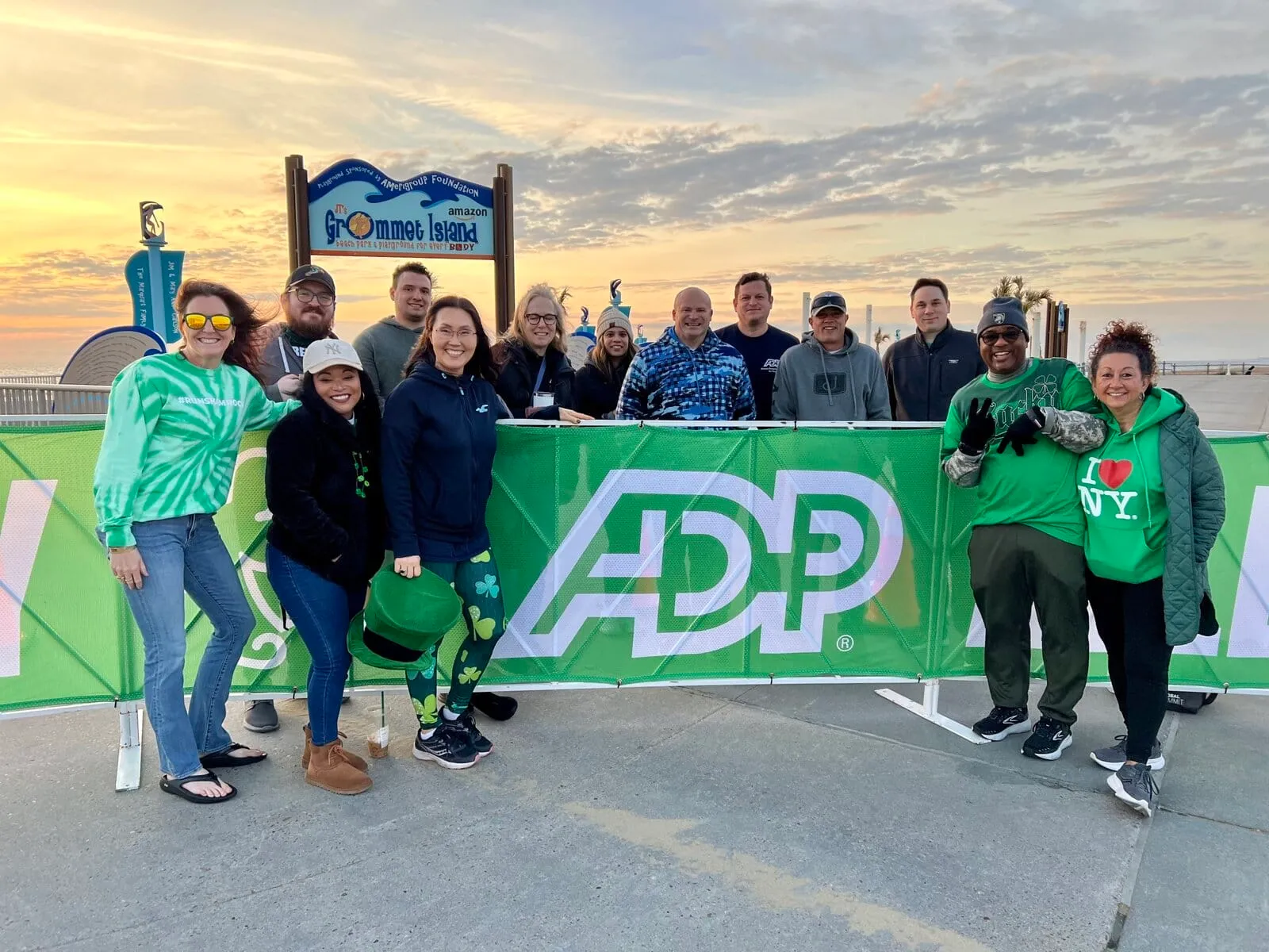 A group of people posing in front of a green banner with the ADP logo and a sign for Grommet Island.